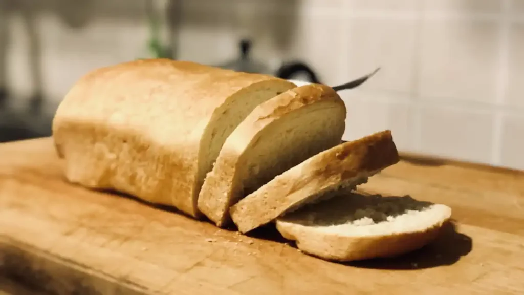 Pão Caseiro Fácil e Rápido: Como Fazer em Casa com Casquinha Dourada e Miolo Macio 2 Pão caseiro fácil e rápido dourado em bancada de cozinha com fatias ao lado